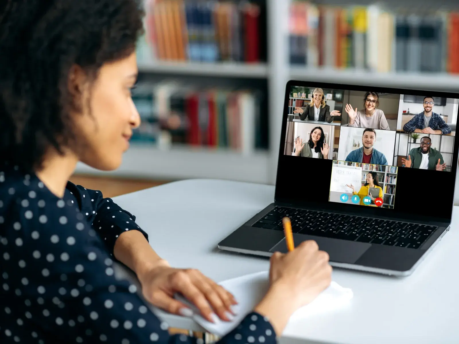Laptopunda sınıf arkadaşları ve öğretmeniyle canlı online derse katılıp not alan öğrenci